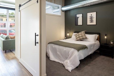 A bedroom with a white bed and a green chair.