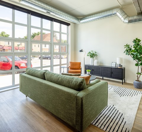 A living room with a green couch and a large window.