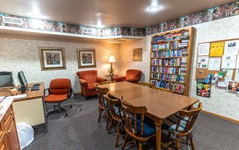 A room with a table, chairs, and a bookshelf filled with books.