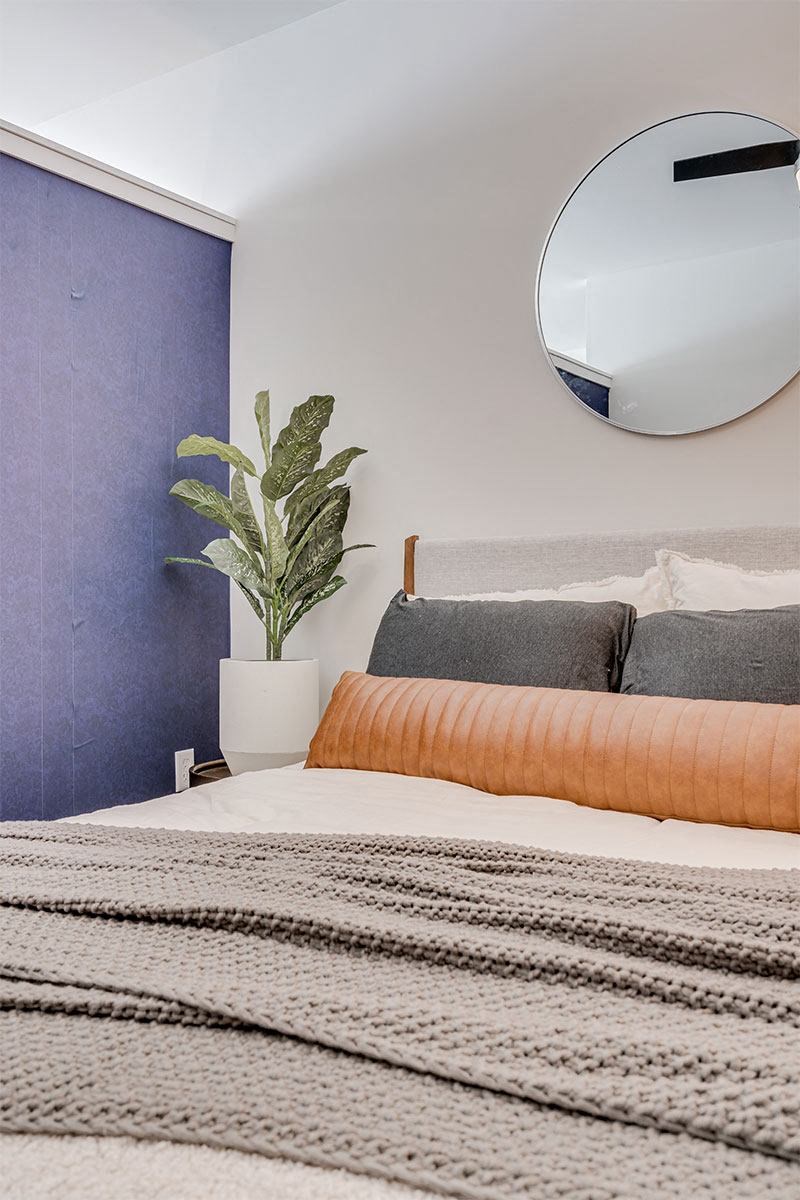 a bedroom with a bed and a mirror on the wall