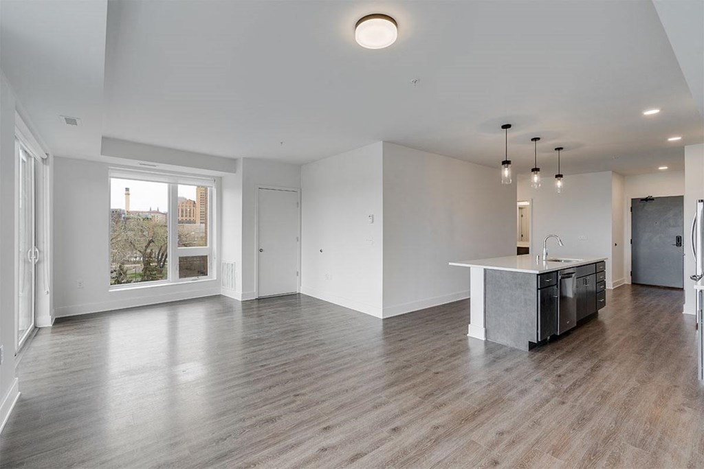 an empty living room and kitchen with a large window