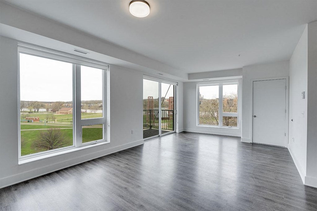 an empty living room with large windows and wood floors