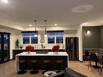 A modern kitchen with a bar stool and a dining table.