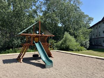 A playground with a green slide and a wooden structure.