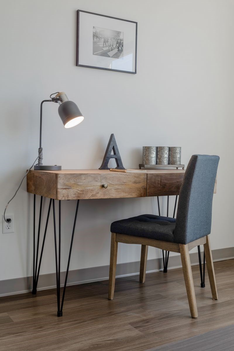A wooden desk with a chair and a lamp on it.