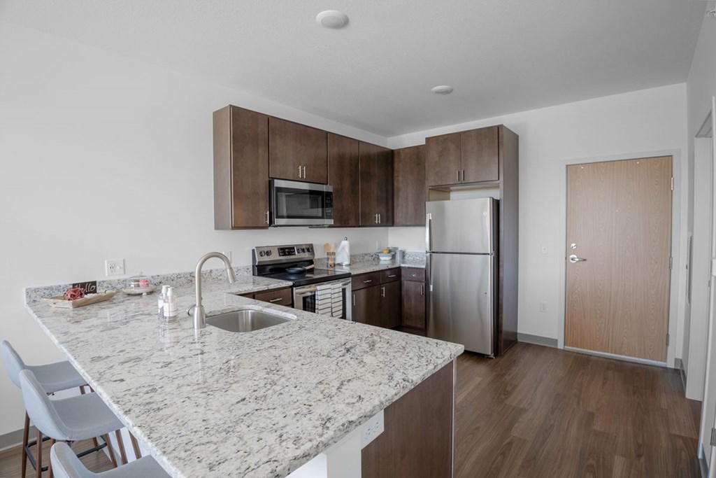 A kitchen with a marble countertop and stainless steel appliances.