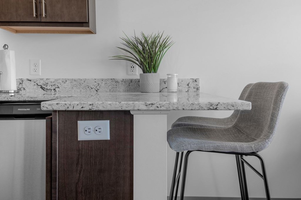 A kitchen counter with a chair and a plant on it.