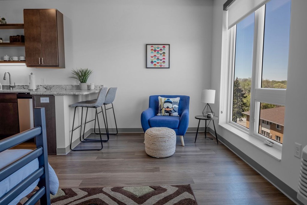 A blue chair with a pillow and a small table in front of a window.