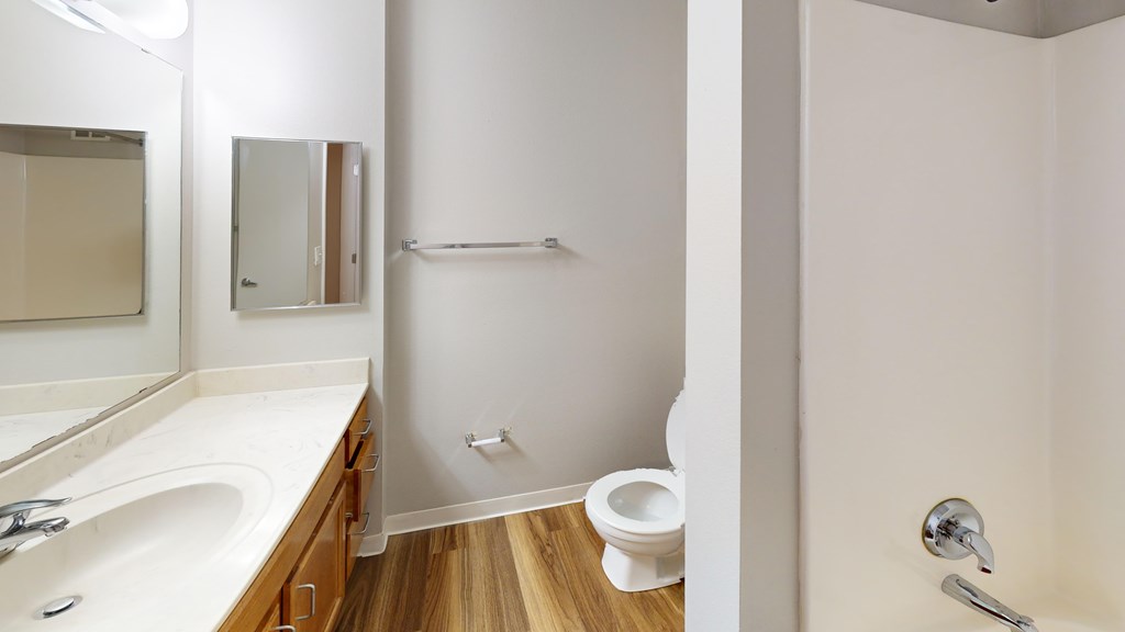 A white bathroom with a toilet, sink, and mirror.