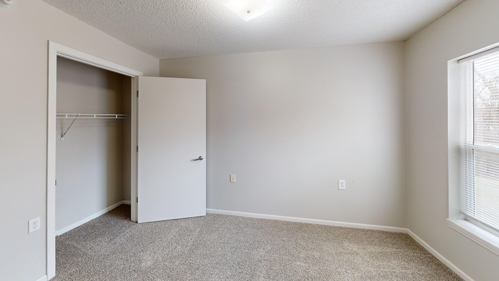 A room with a white door and a grey carpet.