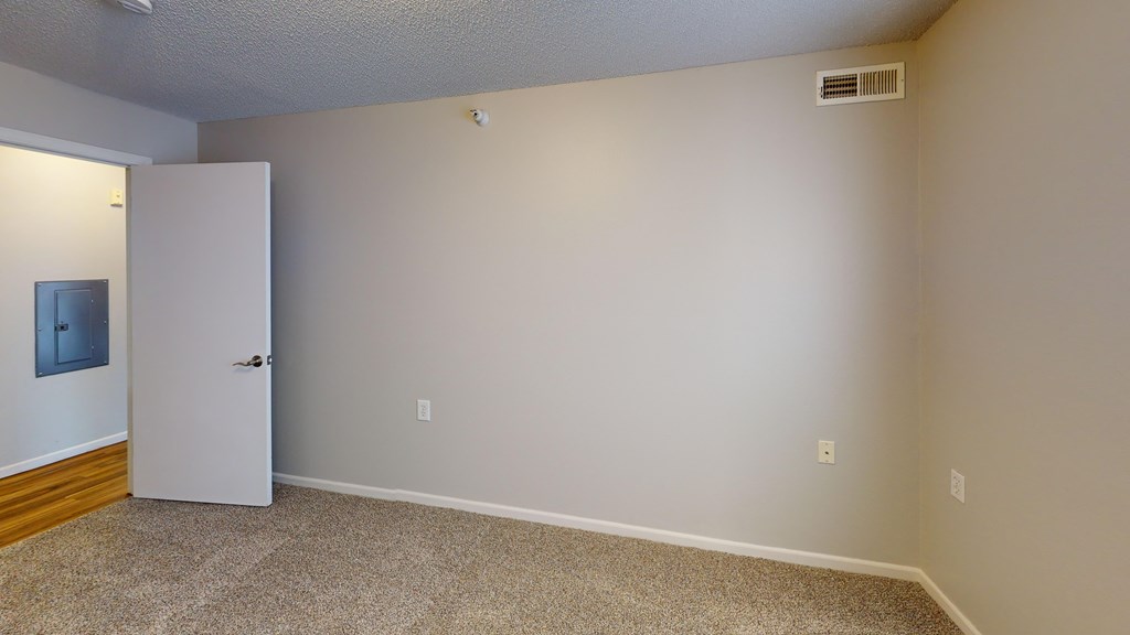 A room with a white door and a carpeted floor.