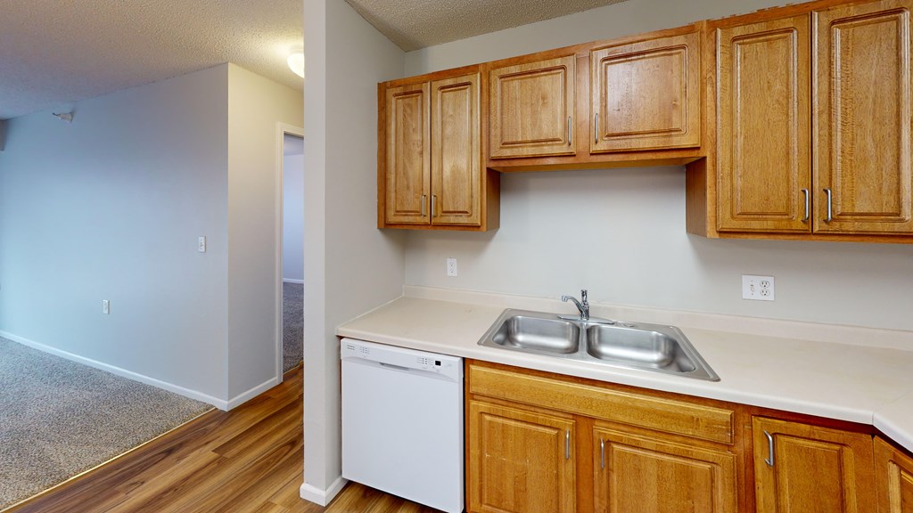 A kitchen with wooden cabinets and a white dishwasher.
