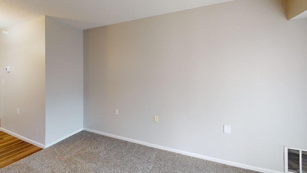 A room with a carpeted floor and a wall-mounted air conditioner unit.