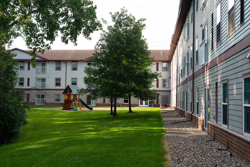 A playground with a slide is in the middle of a grassy area.