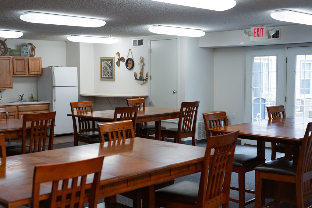 A room with a table and chairs and a refrigerator.