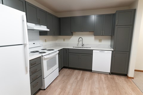 A kitchen with a white fridge, white stove, and white dishwasher.