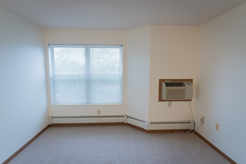 A room with a window and an air conditioner on the wall.