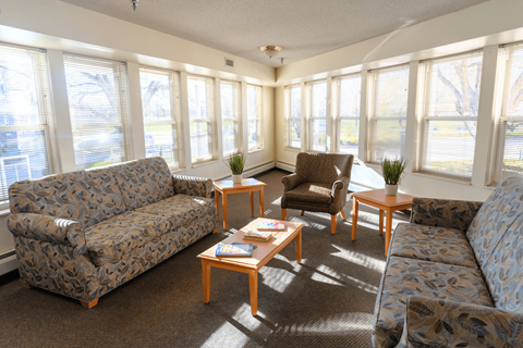 A sunny day in a living room with a couch, chair, and table.