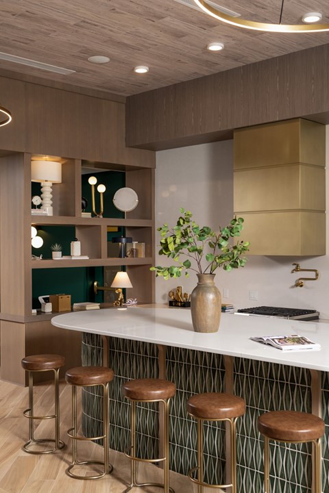 A kitchen with a white counter and brown stools.