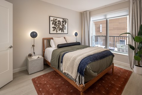 A bedroom with a bed, two lamps, and a painting on the wall.