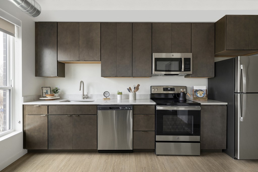 a kitchen with dark cabinets and stainless steel appliances