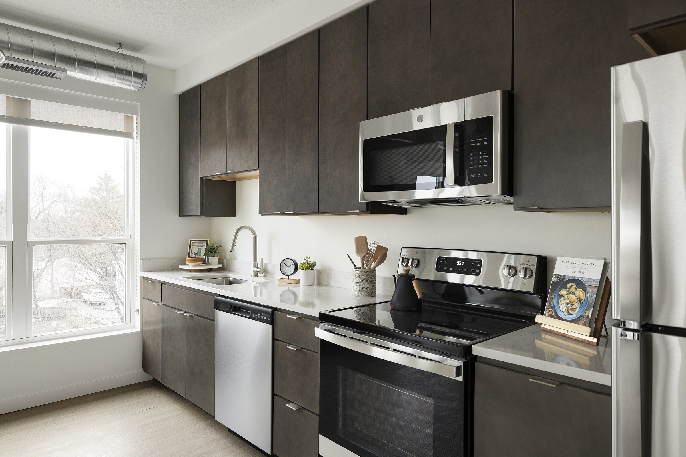 A modern kitchen with a stainless steel refrigerator, oven, and microwave.