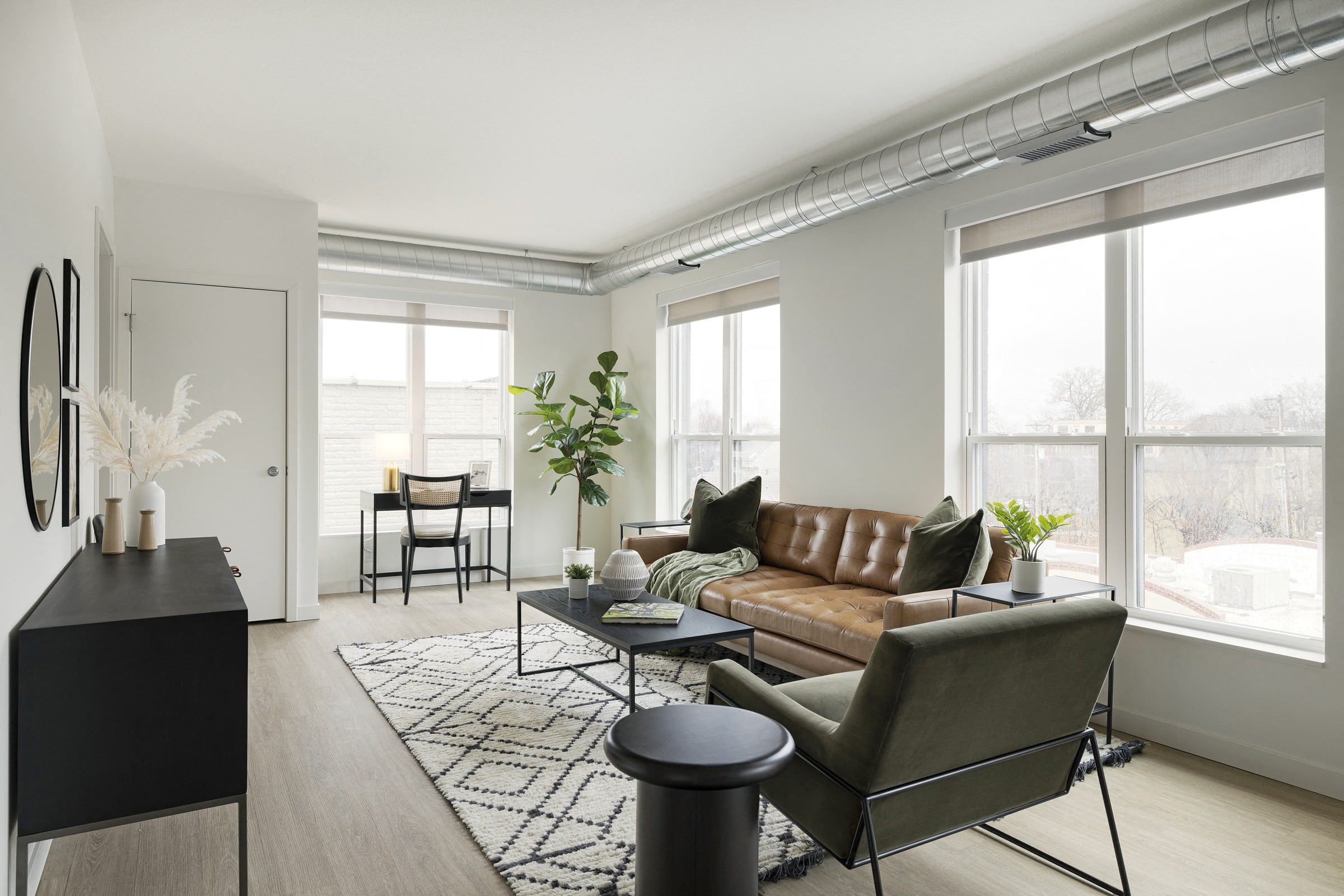 a living room with a brown leather couch and a black and white rug