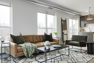 a living room with a brown leather couch and a black and white rug