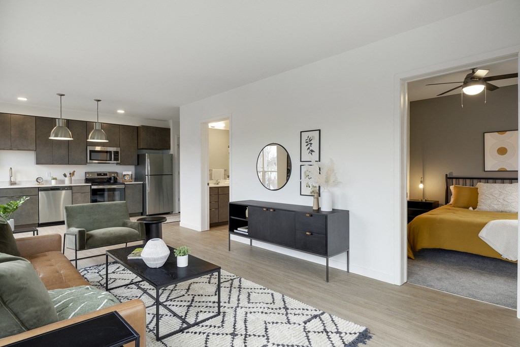 a spacious living room with a kitchenette and bedroom in the background