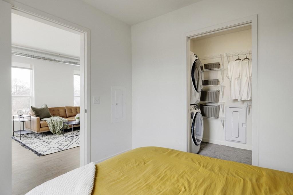 a bedroom with a bed and a closet with a washer and dryer