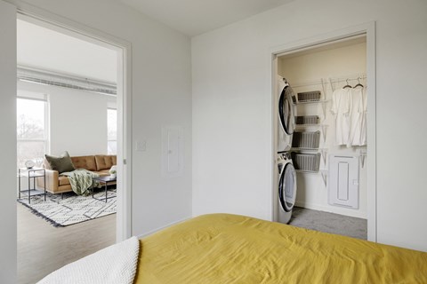 a bedroom with a bed and a closet with a washer and dryer