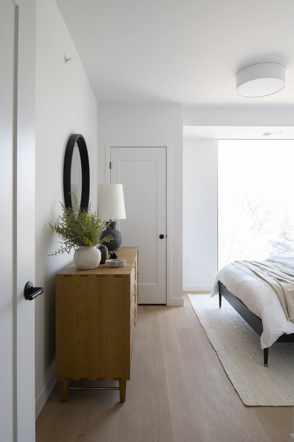a bedroom with white walls and a wooden dresser with a mirror on it