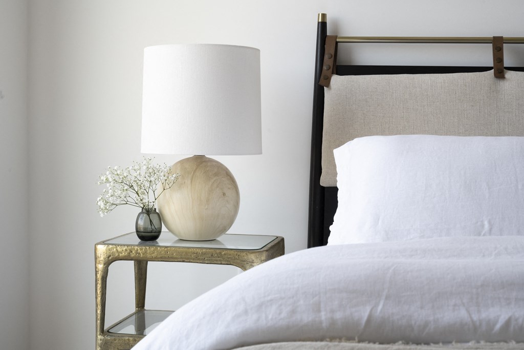 a bedroom with a bed and a nightstand with a lamp and a vase with flowers