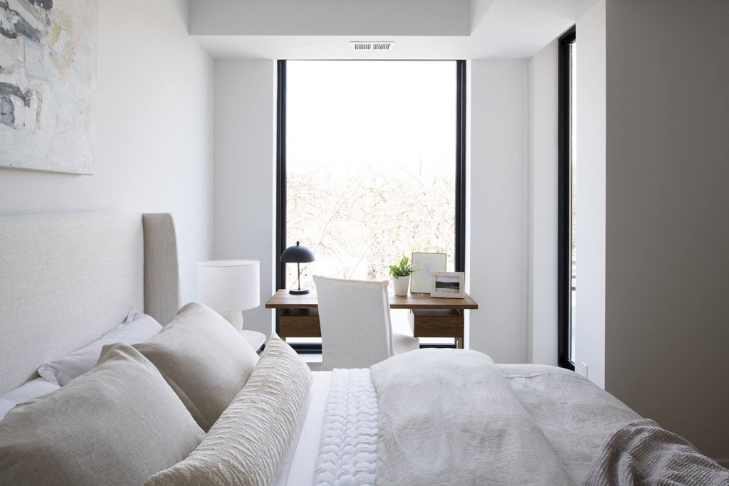 a bedroom with a large bed and a desk in front of a window
