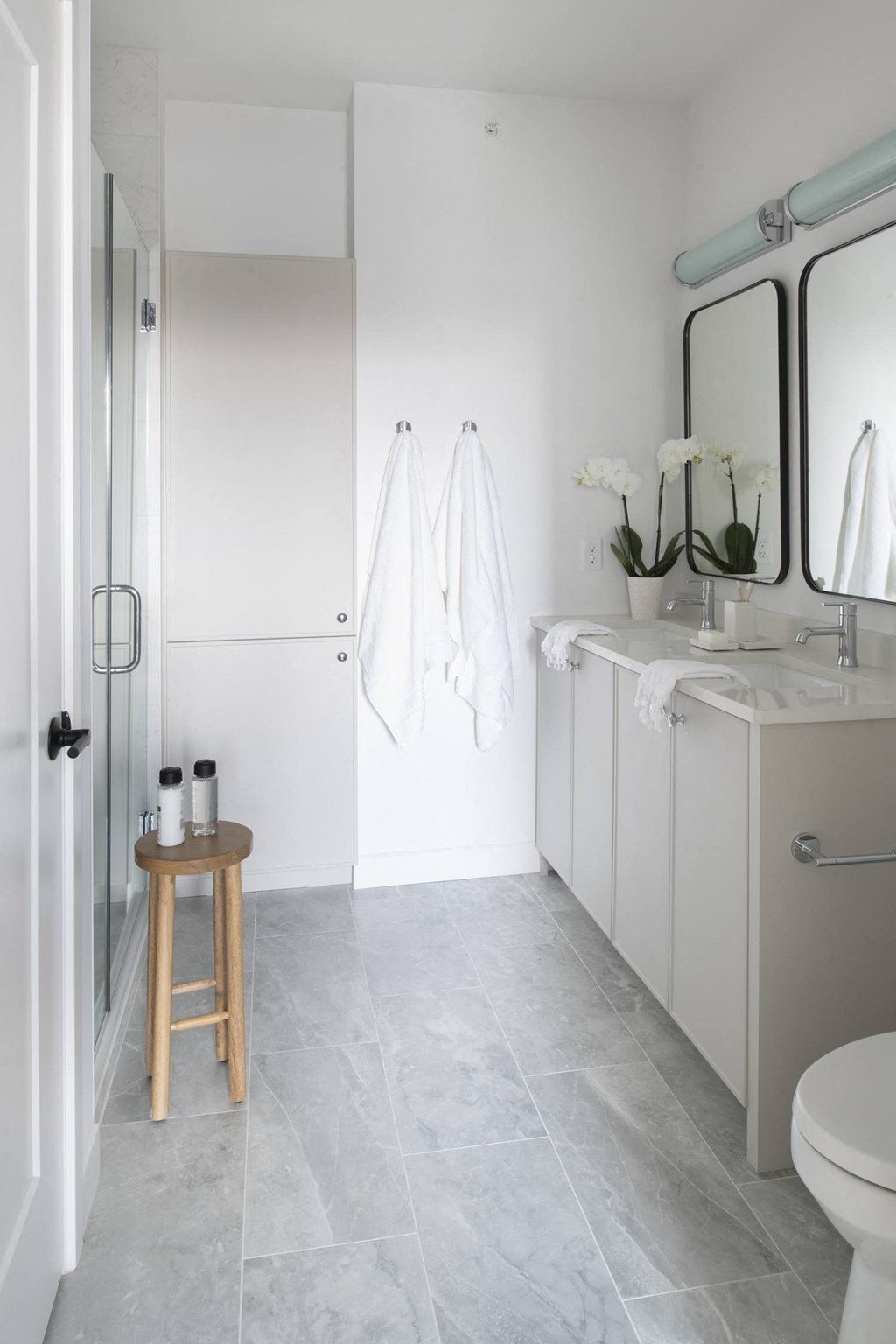 a small stool sits in the corner of a white bathroom