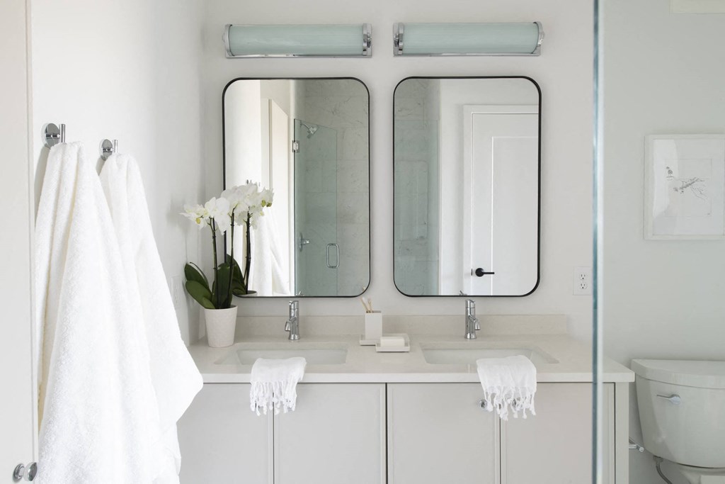 a white bathroom with two mirrors