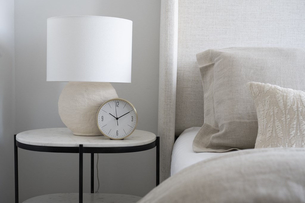 a nightstand with a white lamp and a clock on it