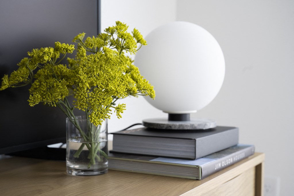 a table with a vase of flowers on top of a stack of books