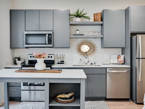 a kitchen with gray cabinets and stainless steel appliances and a white counter top