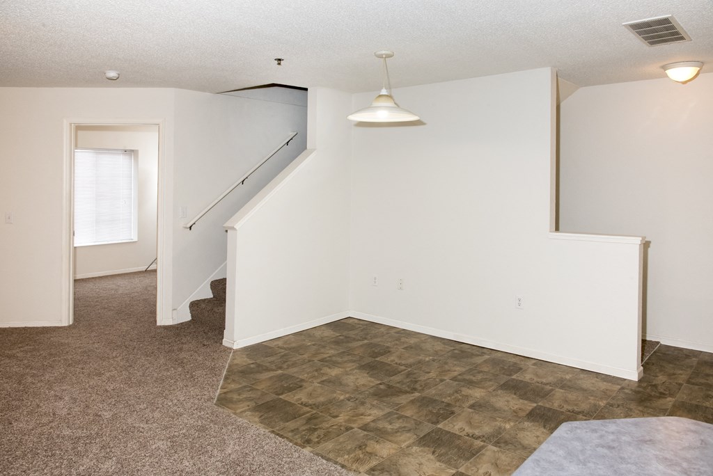 an empty living room with a staircase and white walls