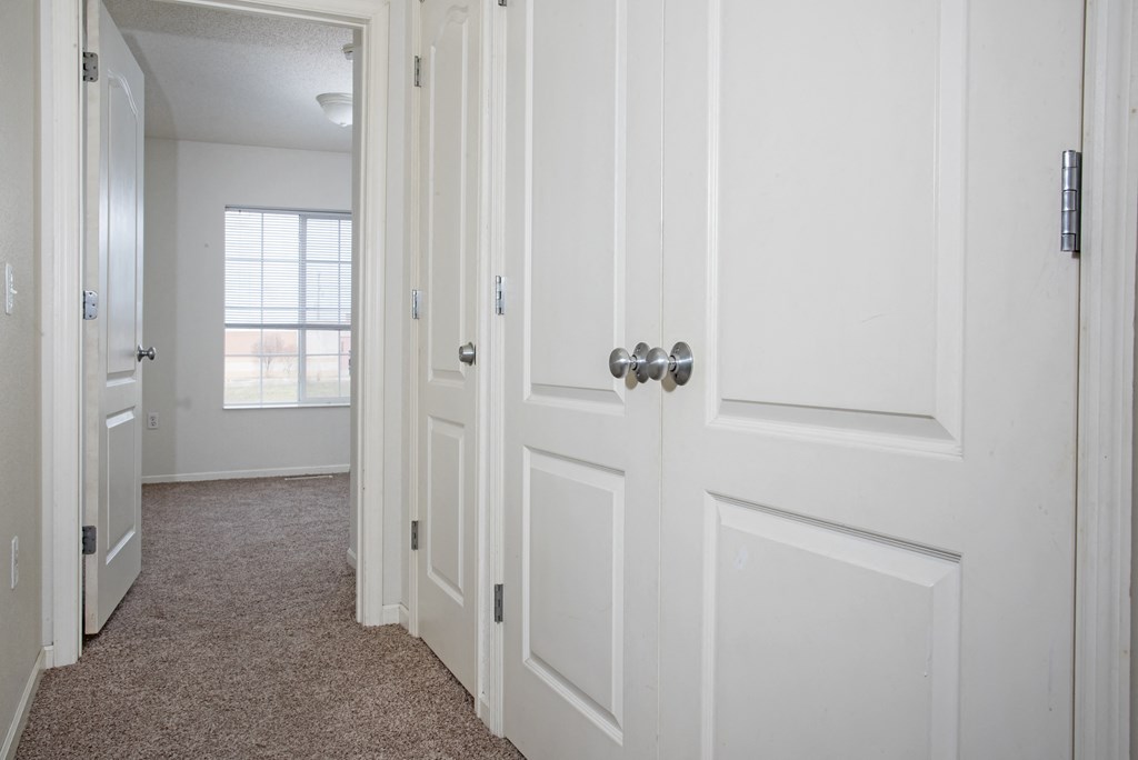 a bedroom with white doors and a carpeted floor and a window