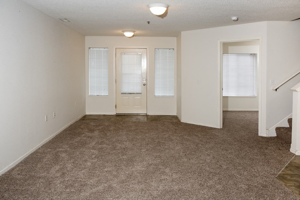 an empty living room with carpeting and white doors