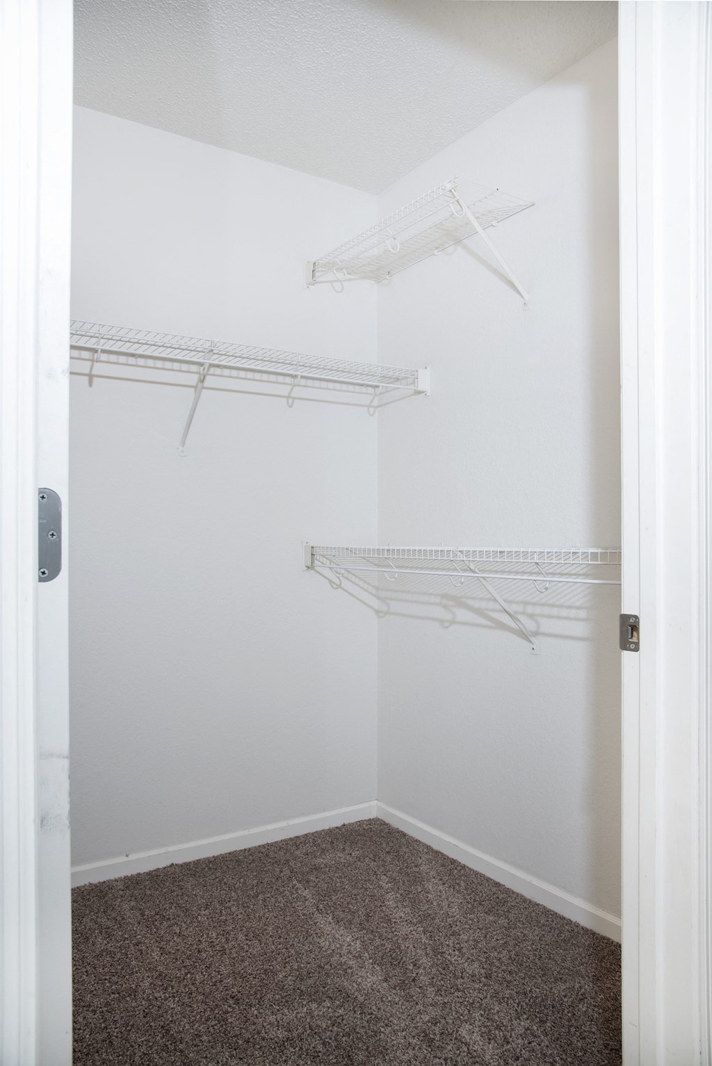 an empty closet with white shelves and white walls and carpet