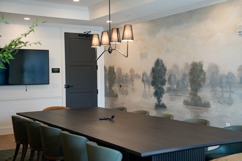 A dining room with a large table and chairs.