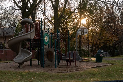 A playground with a slide, swings, and a basketball hoop.