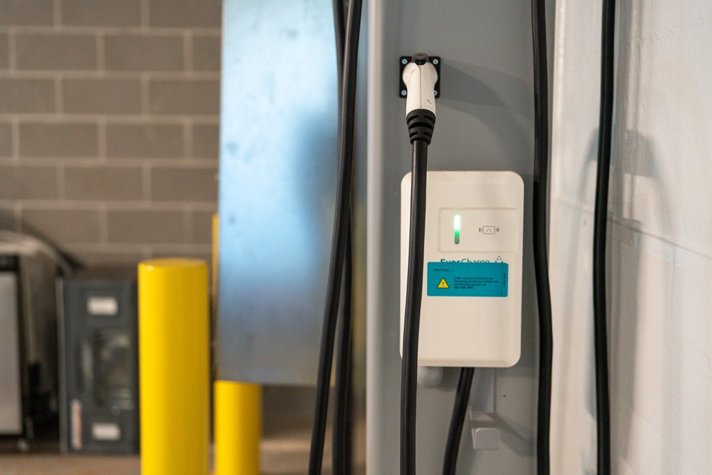 A white charging station with a green light on it.