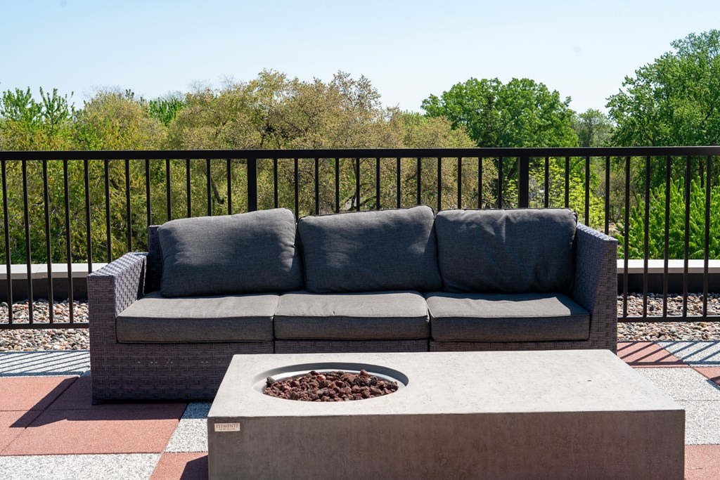 A grey couch with a pillow is on a balcony.