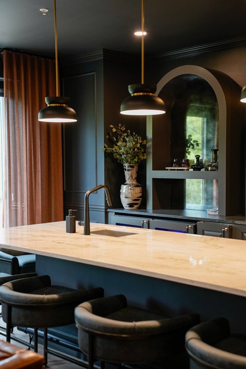 A kitchen with a counter and chairs.