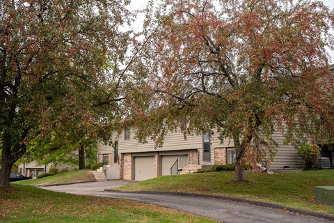 A tree with red leaves in front of a house.