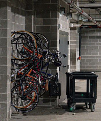 A black cart is parked next to a wall full of bicycles.